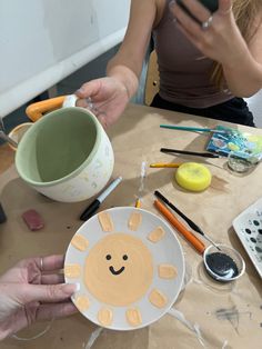 a woman is painting a sun on a paper plate with paint and crayons