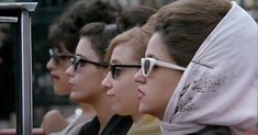 several women wearing sunglasses and head coverings are sitting in a row on a bus