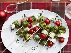 a white plate topped with pasta and veggies on skewers next to a glass of wine