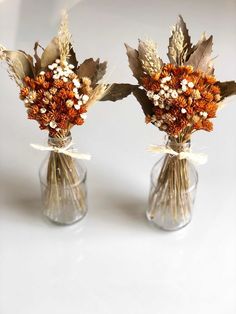 two vases with dried flowers and leaves in them