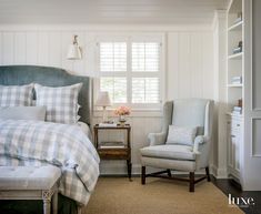 a bed room with a neatly made bed and a chair next to the bed in front of a window