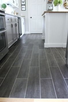 a kitchen with gray tile flooring and stainless steel appliances