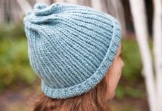 a woman wearing a blue knitted hat with a knot at the top and back