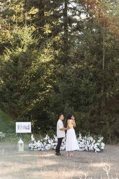 a man and woman standing in front of some trees