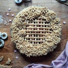 a pie with flowers on it sitting on top of a wooden table next to buttons