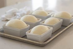 six square trays filled with dough on top of a counter