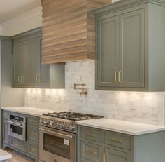 a kitchen with green cabinets and white counter tops, gold trim on the oven hood