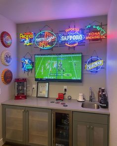 a large television mounted to the side of a wall next to a bar with neon signs on it