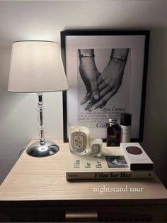 a table with a lamp and some books on it next to a framed poster that says love