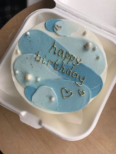 a blue and white birthday cake sitting on top of a plastic container with the words happy birthday written on it