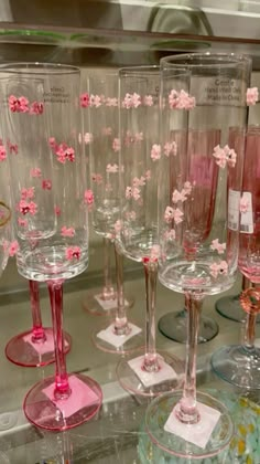 several wine glasses with pink flowers on them are sitting on display in a glass case