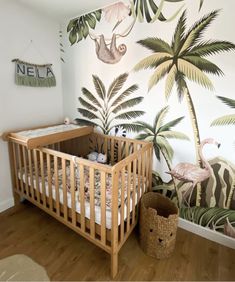 a baby's room decorated with tropical wallpaper and palm trees, including a crib