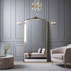 a living room with grey walls and furniture in the corner, along with a chandelier