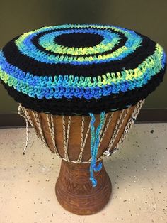 a crocheted hat is sitting on top of a wooden stand with chains around it