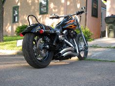 a black motorcycle parked in front of a building on the side of a road next to grass and trees