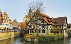 an old building on the side of a river in germany with people walking along it