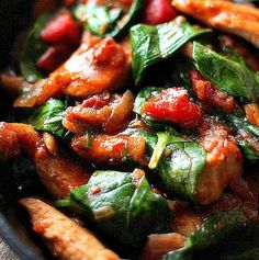 a bowl filled with meat and spinach covered in sauce