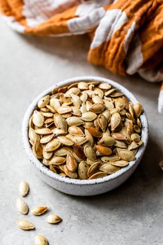 a white bowl filled with pumpkin seeds on top of a table