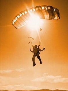 a person is flying through the air with a parasail in their hand and sun shining behind them