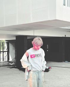 a man with pink hair standing in front of a building