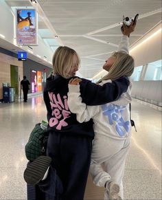 two women hugging each other in an airport