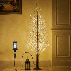 a lighted christmas tree next to an old fashioned phone and charger on the floor