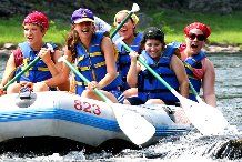 a group of people riding on the back of a raft down a river