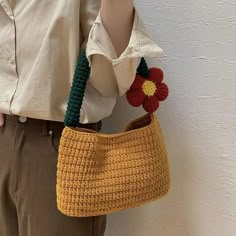 a woman holding a crocheted purse with a flower on it's handle