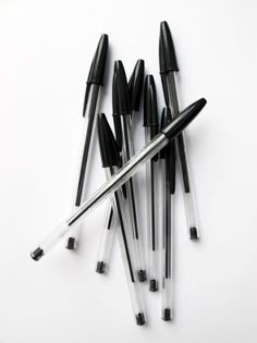 several pens are lined up next to each other on a white surface with black tips