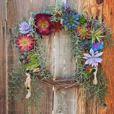 a wreath with succulents hanging on a wooden fence