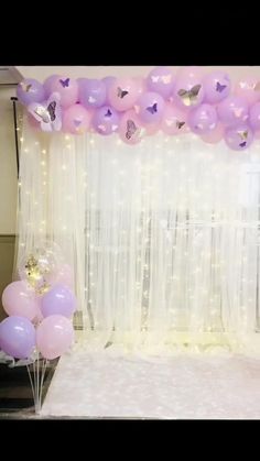 balloons and streamers are on the floor in front of a window with sheer curtains