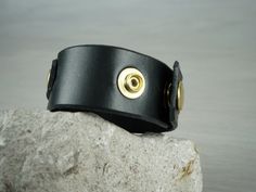 "BLACK LEATHER CUFF BRACELET WITH LINK We realize all our items with prime full grain italian leathers and made in Italy hardware. The quality and longevity of our creations is what brought us to choose only the best raw materials for our products. This bracelet is made of full grain black leather. It has an adjustable button closure that gives it a uinque look. It has a leather strap on it connected by a metal link that gives it this special design. This bracelet has a unique looking design, bu Black Leather Bracelet For Everyday Use, Everyday Black Leather Bracelet, Leather Bracelet With Black Band For Everyday, Everyday Leather Bracelets With Black Band, Black Leather Cuff Bracelet, Leather And Brass, Women In Black, Design Bracelet, Leather Cuffs Bracelet