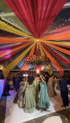 several people standing under a colorful canopy at a party