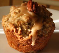 a close up of a muffin on a plate with pecans in the background