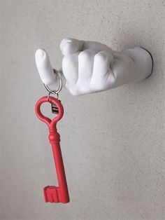 a hand holding a red key attached to a wall