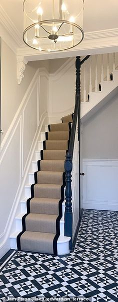 a staircase leading up to the second floor in a house with black and white tiles