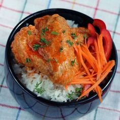 a black bowl filled with rice, carrots and meat on top of a table