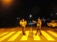 two people walking across a crosswalk at night