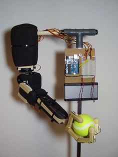 a robot is holding a tennis ball and racket