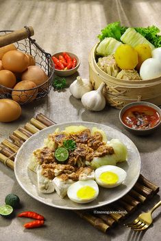 an assortment of food on a table with chopsticks and eggs in baskets next to it