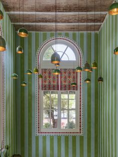 a room with green and white stripes on the walls, lights hanging from the ceiling