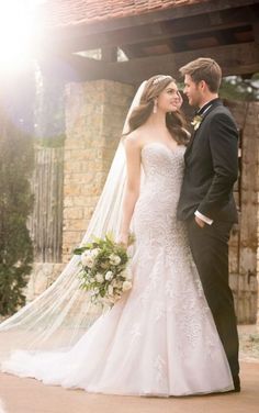 a bride and groom pose for a photo in front of an old brick building with the sun shining on them