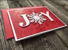 a red and white christmas card with snowflakes on the front, which reads joy