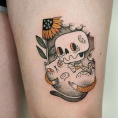 a woman's thigh with a skull and sunflower tattoo on it, holding a baby koala