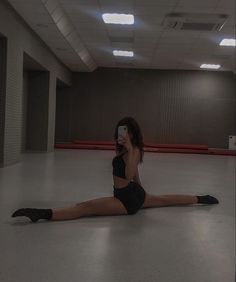 a woman sitting on the floor taking a selfie with her cell phone in an empty room