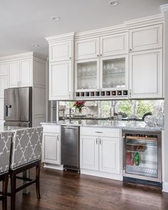 a kitchen with white cabinets and stainless steel refrigerator freezer combo in the center, next to a dining room table