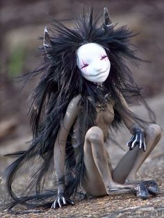 a creepy doll with long hair sitting on the ground