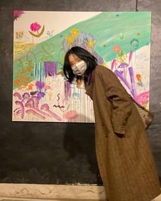 a woman wearing a face mask in front of a painting