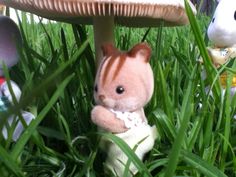 small stuffed animals sitting in the grass next to a mushroom