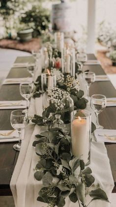 a long table is set with candles and greenery for an elegant dinner or party